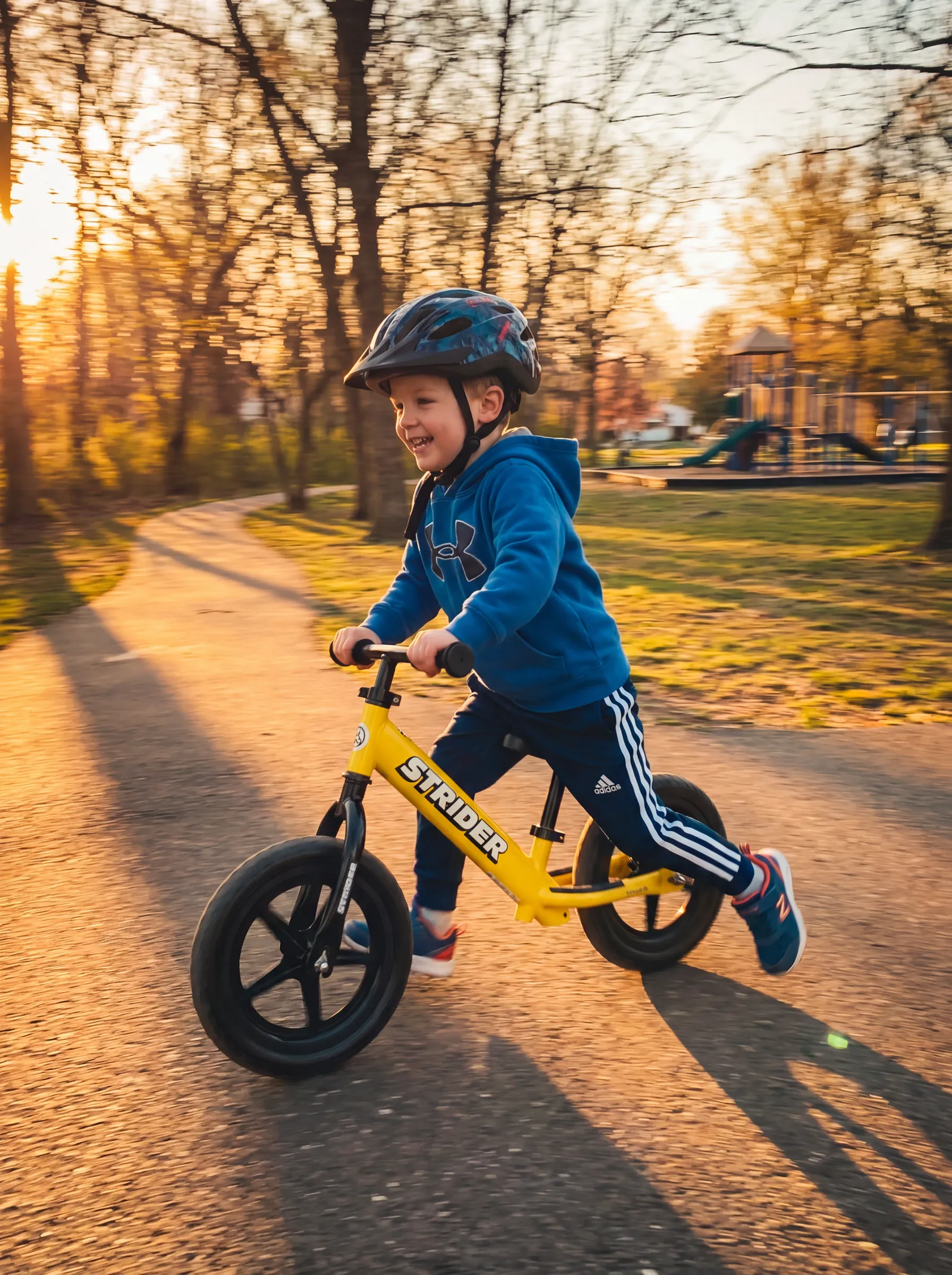 A confident child gliding on a Freesol Strider balance bike outdoors in golden light
